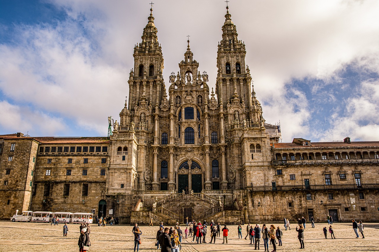 Vista frontal da Catedral de Santiago de Compostela com pessoas reunidas na praça em frente.