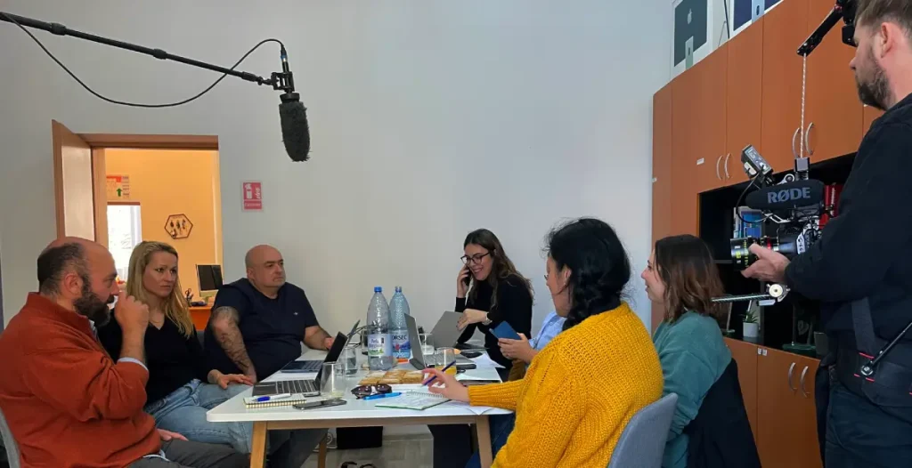 Project partners discussing around a big table. Rusaalka Films team is recording the meeting.