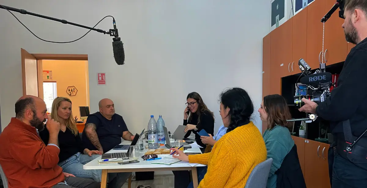 Project partners discussing around a big table. Rusaalka Films team is recording the meeting.